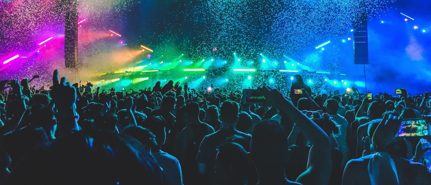 Publikhav framför konsertscen med färgsprakande landskap som scenografi.