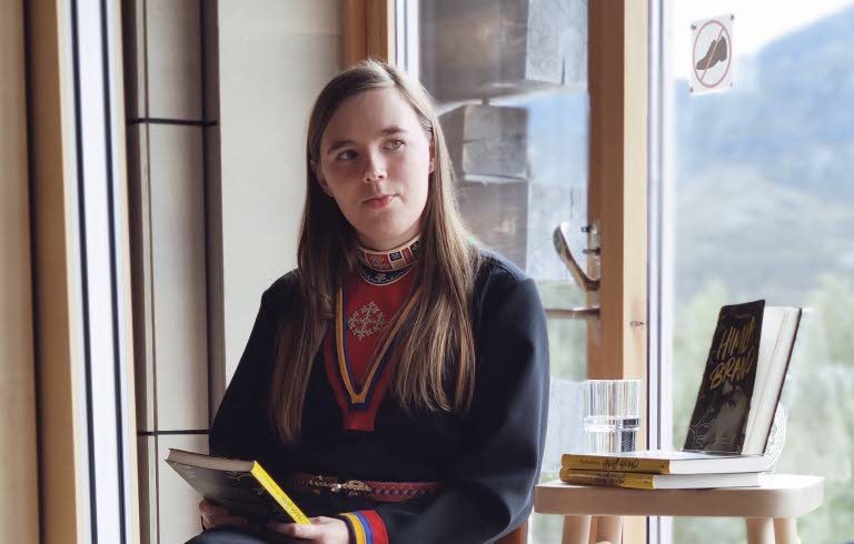 Kvinna samtalar vid fönster.