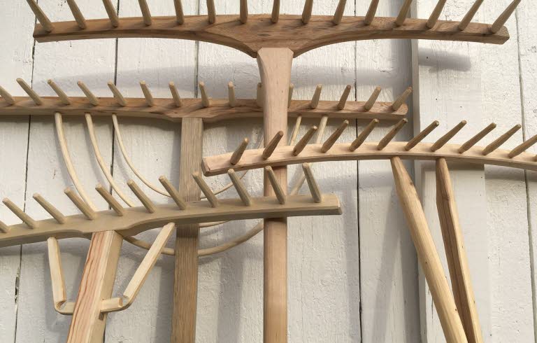 Fyra handtillverkade träräfsor mot en vägg.