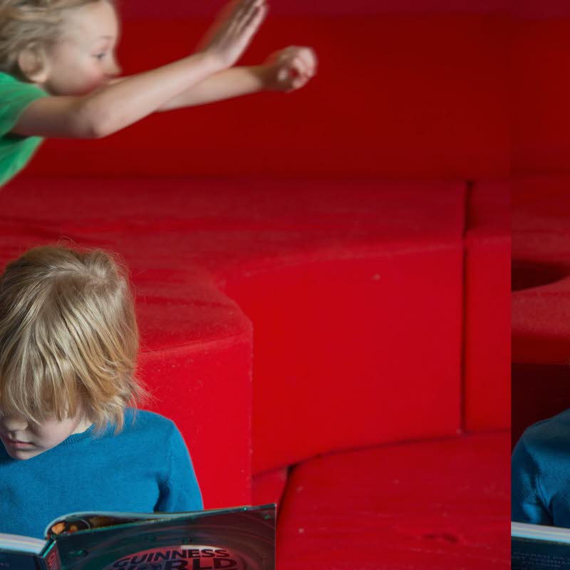 Ett läsande och ett flygande barn i bakgrunden