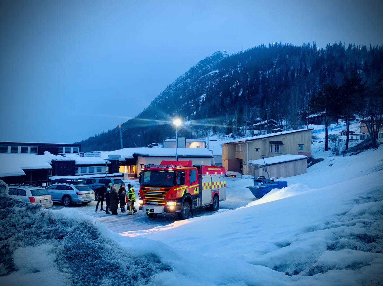 Vinterbild med människor som samtalar bredvid en brandbil.