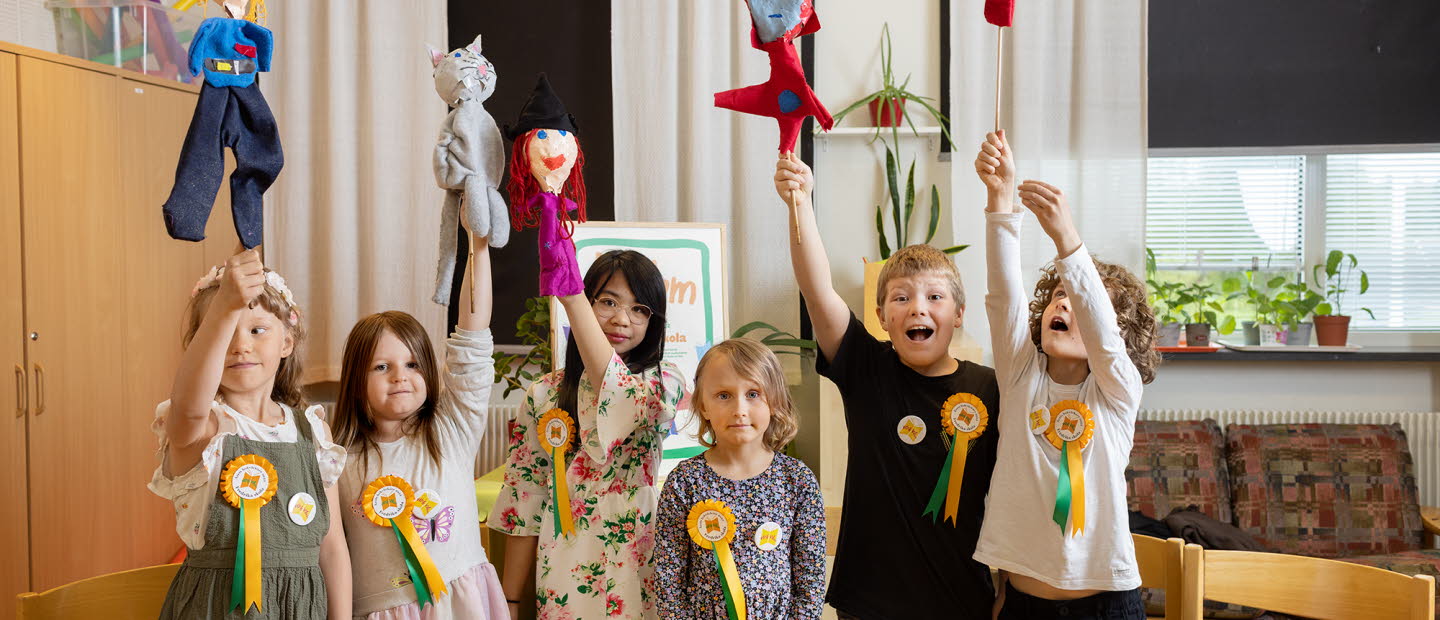 Sex barn, såväl pojkar som flickor, håller upp händerna, har prisrosett fastsatta på sina tröjor.