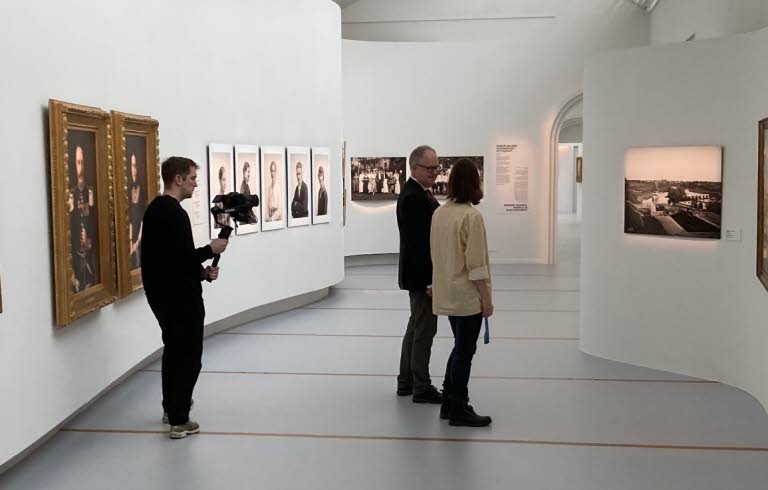 Två personer tittar på konst på Östergötlands museum. I bakgrunden står en filmare och filmar.