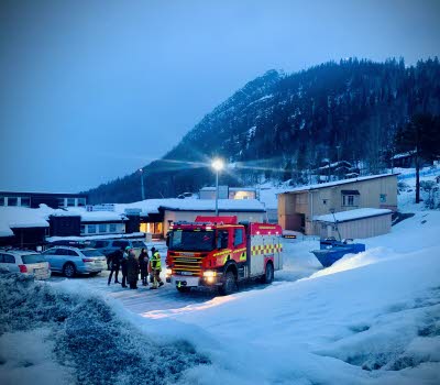 Vinterbild med människor som samtalar bredvid en brandbil.