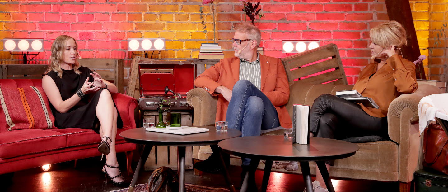 Three people are sitting and talking in a lounge setting.