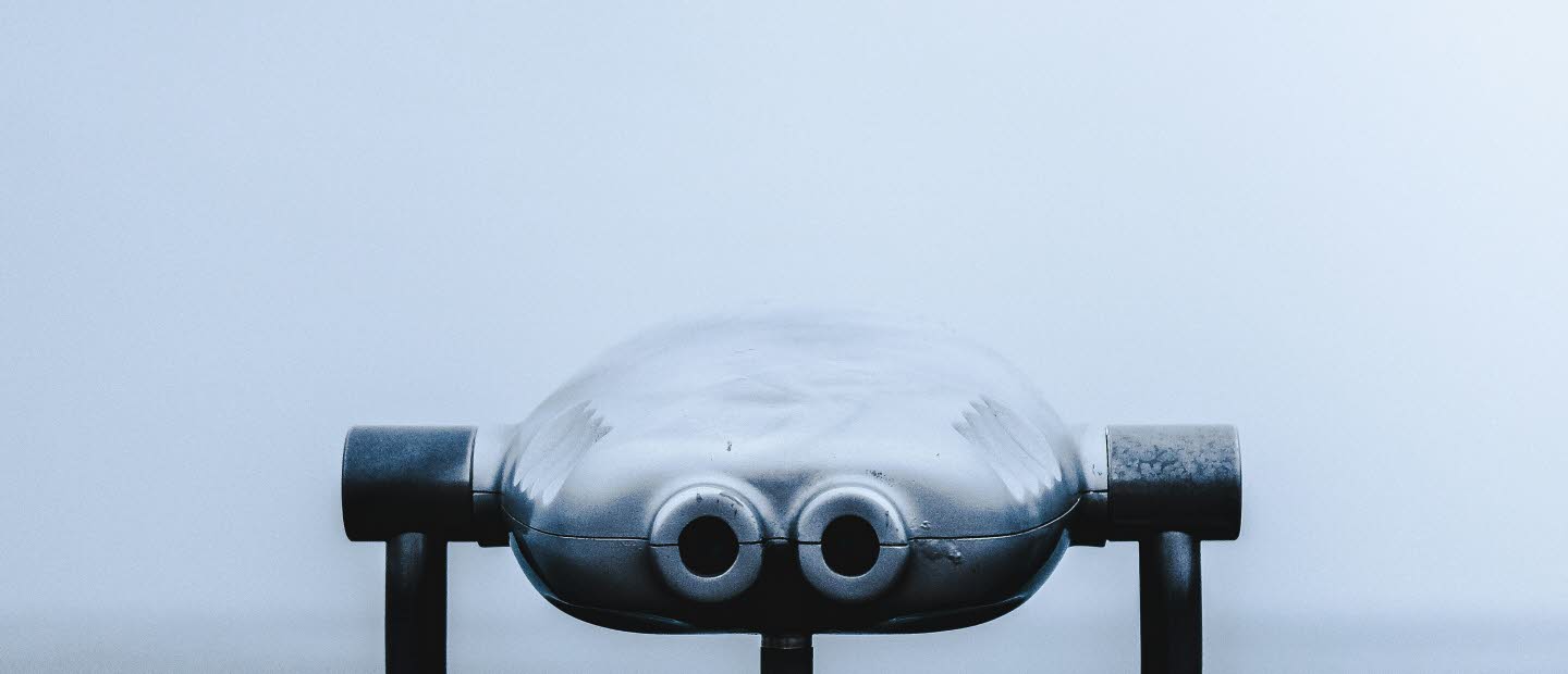 Foto av en kikare i fören på en båt. Dimmigt hav i bakgrunden. 