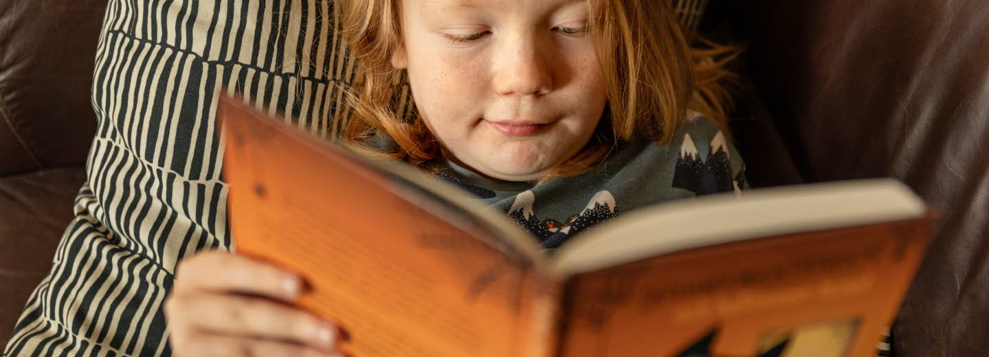 Foto på barn som ligger och läser en bok. Foto: Susanne Kronholm