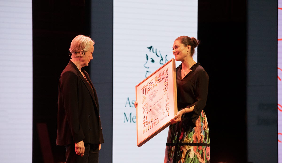 H.K.H. Kronprinsessan Victoria håller upp prisdiplomet framför Eva Lindström som tilldelas Astrid Lindgren Memorial Award 2022. Foto: Susanne Kronholm.