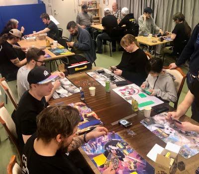 Unga sitter runt ett bord och spelaar brädspel.