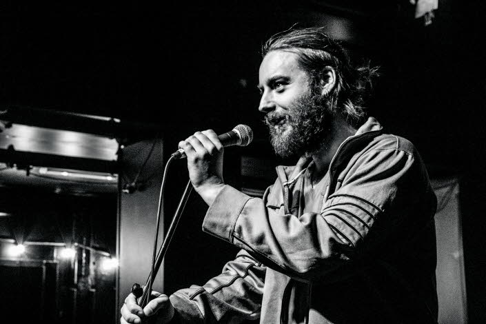 Photo of christian on stage talking into a microphone.