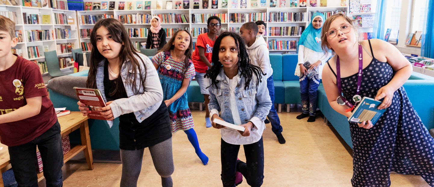 Eleverna hoppar, snurrar och gör armhävningar under bokgympan på skolbiblioteket.