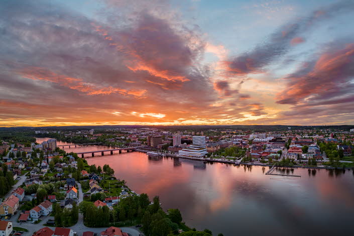 Drönarvy över Umeå och älven i solnedgång.