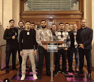 Bild på en grupp mestadels unga män bakom en talarstol som visar att de är i Riksdagen.