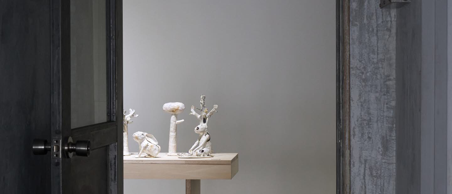 En dörr står öppen, i rummet skymtas vita skulpturer uppradade på ett bord.