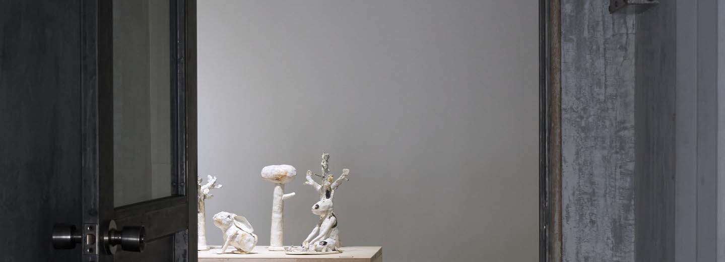En dörr står öppen, i rummet skymtas vita skulpturer uppradade på ett bord.
