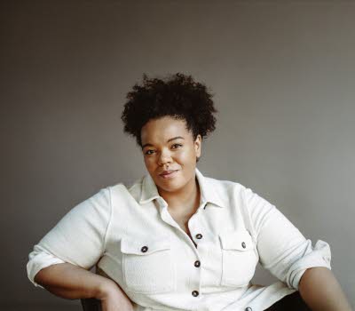 Maria Fröhlich is sitting in a relaxed posture, wearing a white shirt.