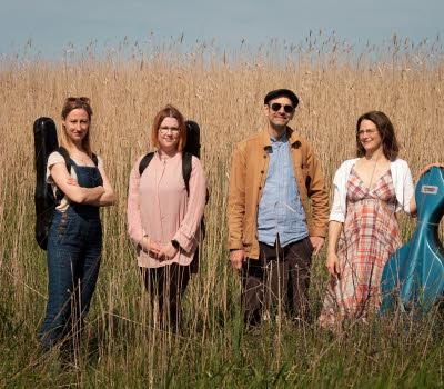 Fyra musiker i utomhusmiljö.