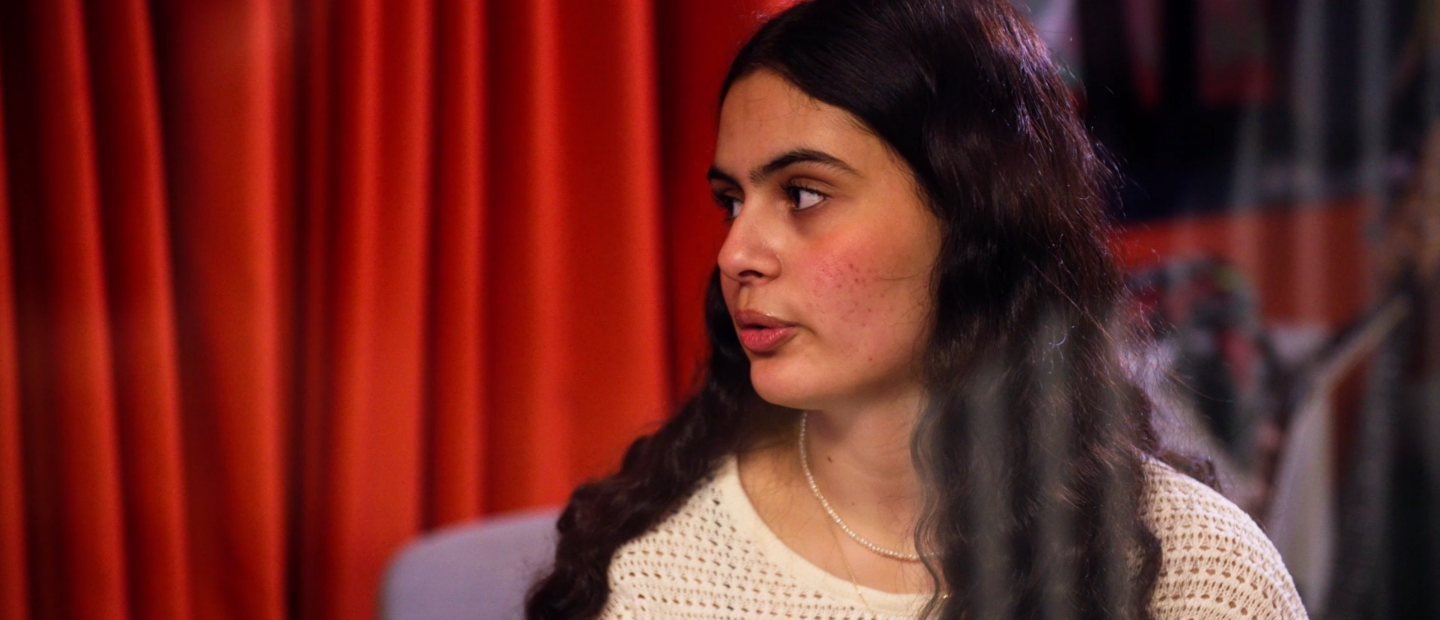 En kvinna som står framför ett draperi.