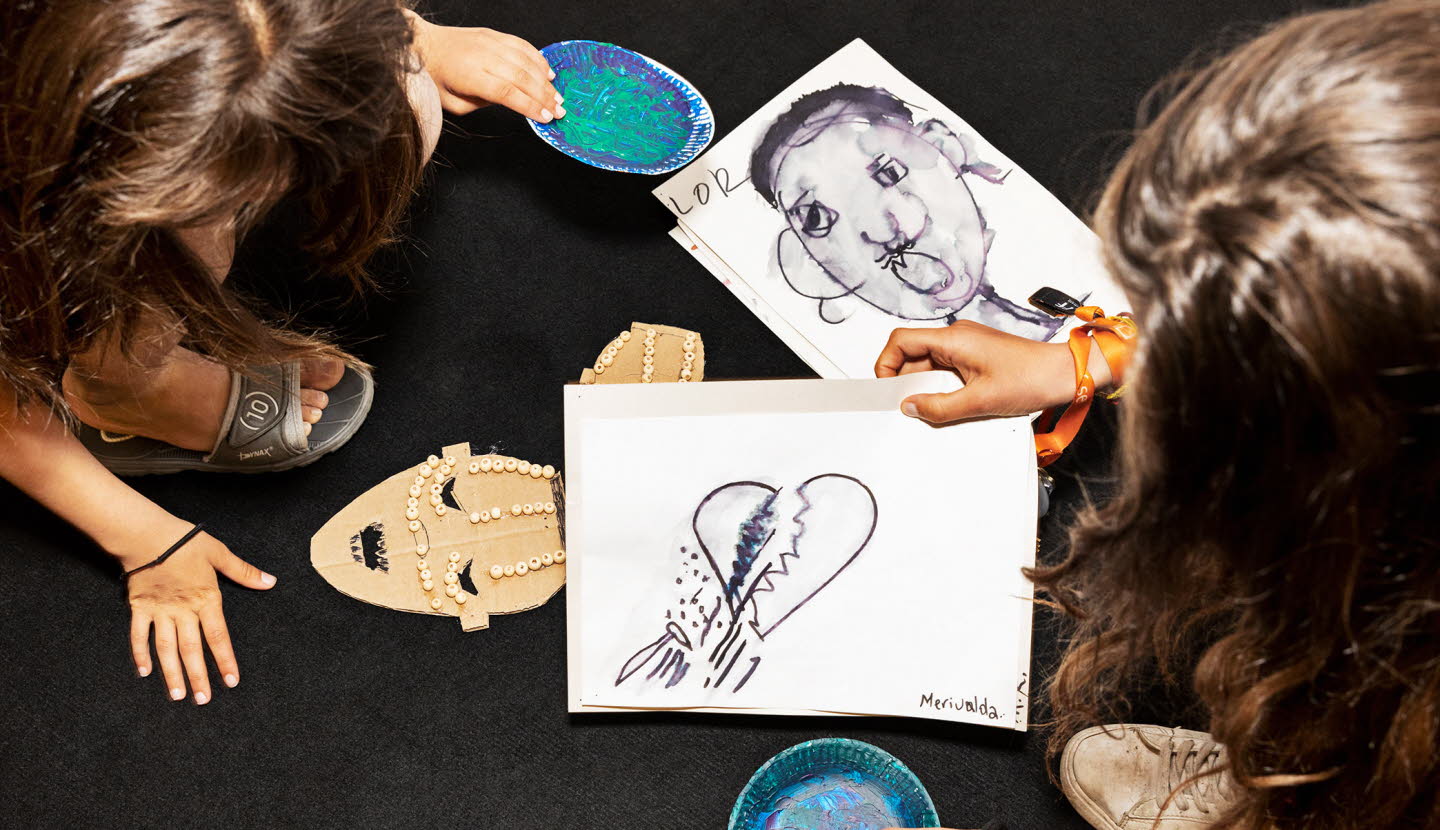 Två personer uppifrån som har teckningar framför sig, med bland annat ett brustet hjärta.