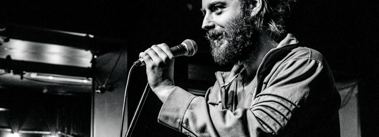 Photo of christian on stage talking into a microphone.