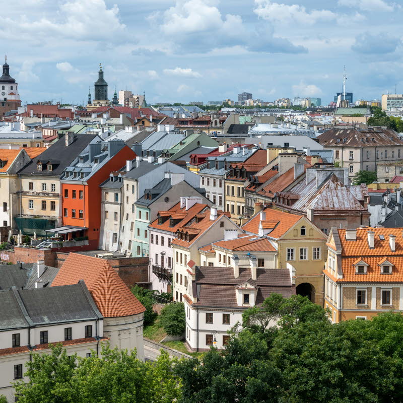 Bild över flera hustak i staden Lublin. I bakgrunden skymtas ett kyrktorn. Vädret är sol med växlande molnighet.