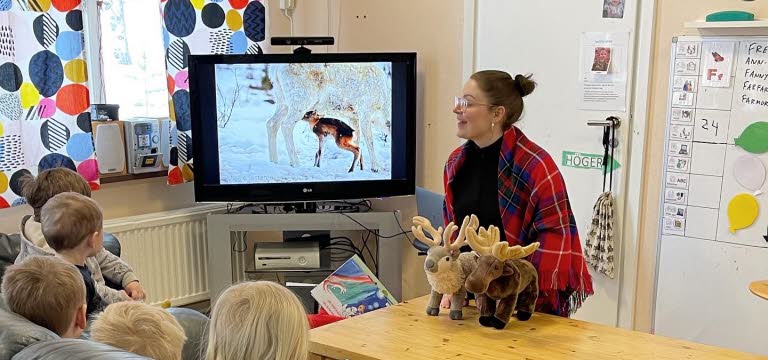 Berättarstund med små barn som tittar på bild på renar.