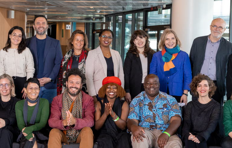 Gruppbild på partners. 18 personer står bakom och sitter i en soffa. De ser alla glada ut och tittar in i kameran.