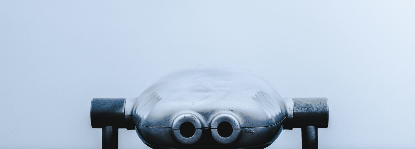 Foto av en kikare i fören på en båt. Dimmigt hav i bakgrunden. 