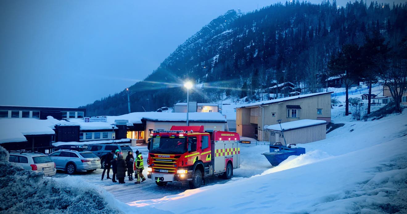 Vinterbild med människor som samtalar bredvid en brandbil.