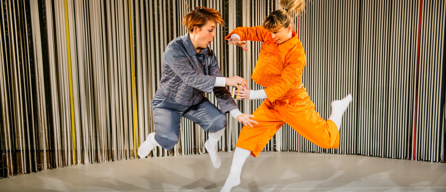 Two dancers jumping while holding a can. 