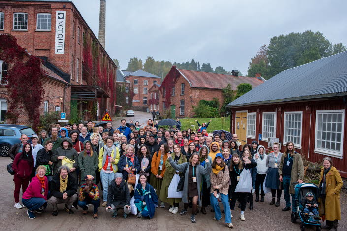 Gruppbild på nätverket utomhus mellan tegelhus och ett trähus.