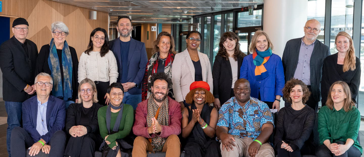 Gruppbild på partners. 18 personer står bakom och sitter i en soffa. De ser alla glada ut och tittar in i kameran.