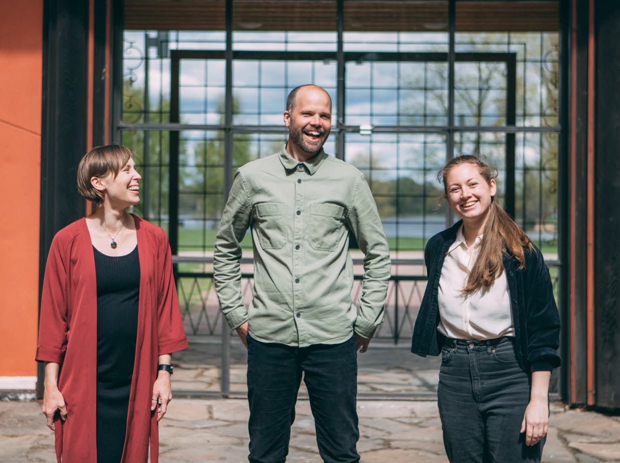 Sara Jane, Olof Göthlin och Tove Klang från Scenbruket står framför byggnaden. Det är sommar och de ser glada ut.