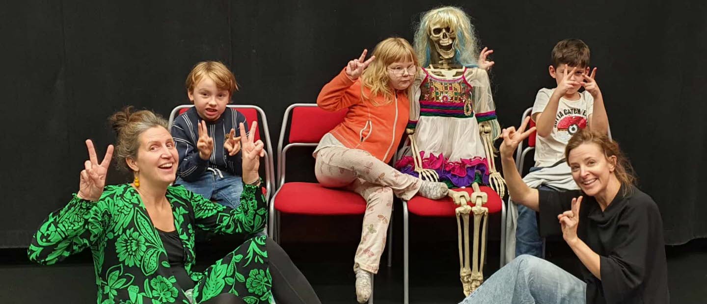 Två pedagoger och tre barn poserar med ett pyntat skelett.