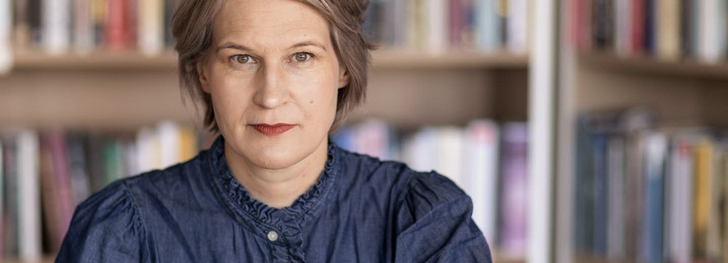Porträttfotografi av en medelålders kvinna, Kulturrådets generaldirektör. I bakgrunden bokhyllor med böcker.