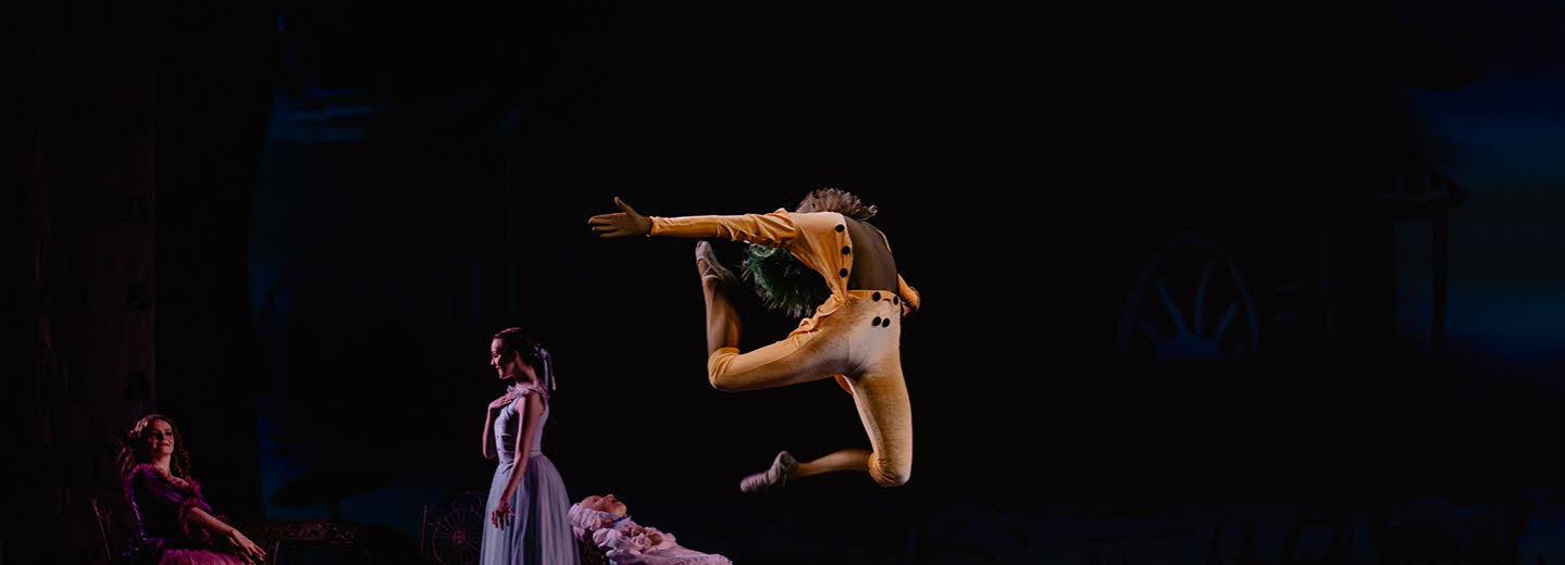 Uppträdande på scen med dansare. En man i orangea kläder kastar sig upp i luften.