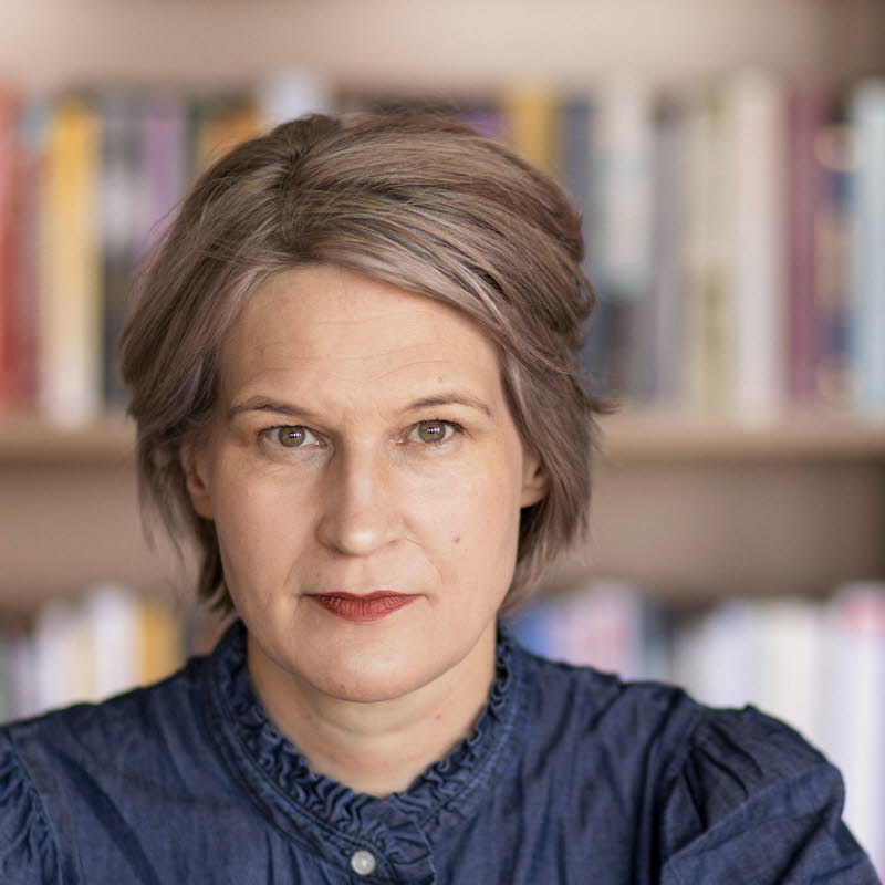 Porträttfotografi av en medelålders kvinna, Kulturrådets generaldirektör. I bakgrunden bokhyllor med böcker.