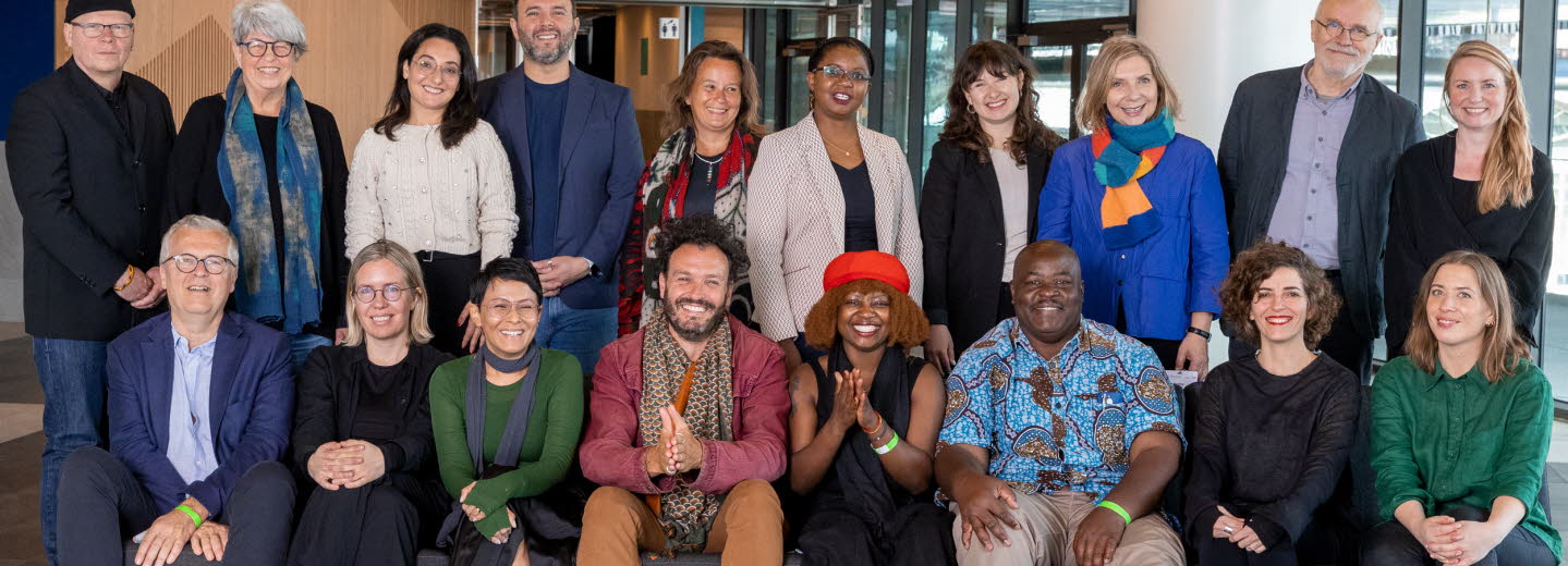 Gruppbild på partners. 18 personer står bakom och sitter i en soffa. De ser alla glada ut och tittar in i kameran.