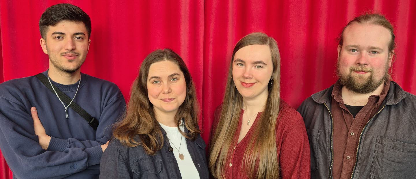 Gruppbild av två kvinnor och två män framför ett rött draperi. 