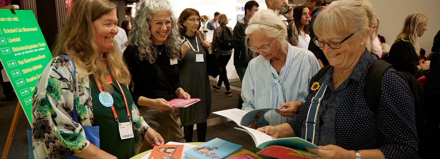 Människor läser i broschyrer i Kulturrådets monter på Bokmässan. 