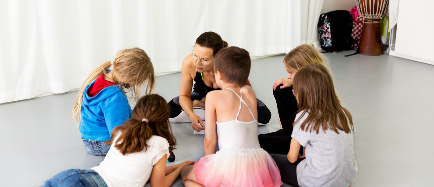 Barn sitter och ligger i en ring och pratar tillsammans med en vuxnen. 