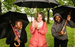 Three people from PRAESA with umbrellas on a rainy day in Stockholm