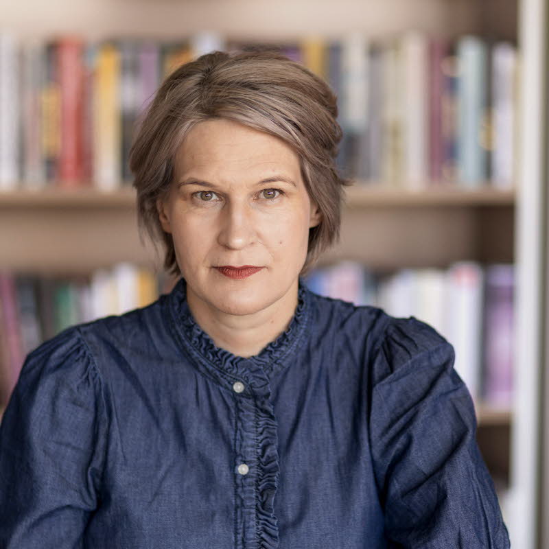 Porträttfotografi av en medelålders kvinna, Kulturrådets generaldirektör. I bakgrunden bokhyllor med böcker.