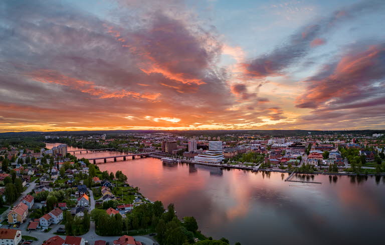 Drönarvy över Umeå och älven i solnedgång.