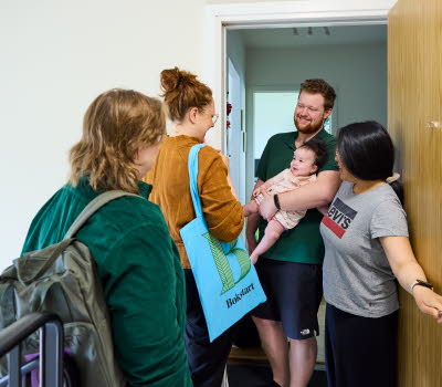 Två medarbetare som arbetar med Bokstart gör ett hembesök. Möter en familj i trapphuset.
