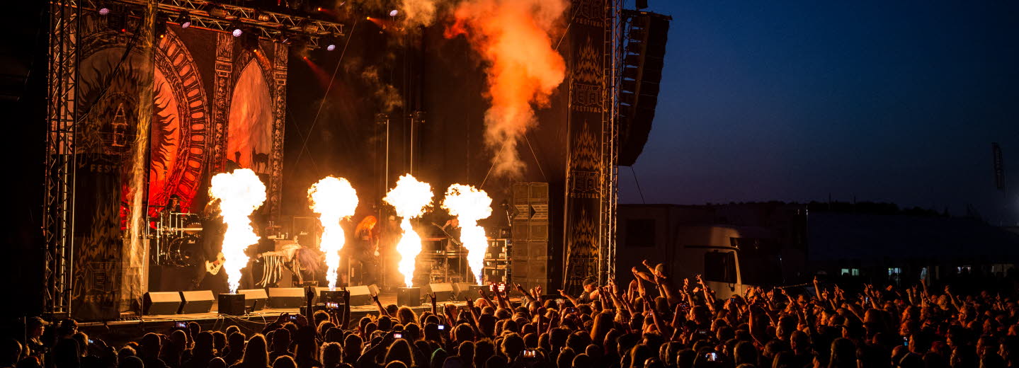 An outdoor music concert with fireworks on stage.
