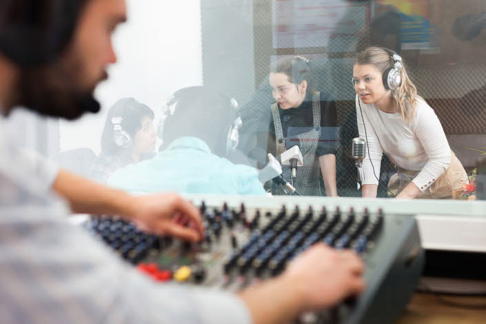 Radioinspelning. Man vid mixerbord och tre tjejer och en man samtalar med mikrofoner och headsets.