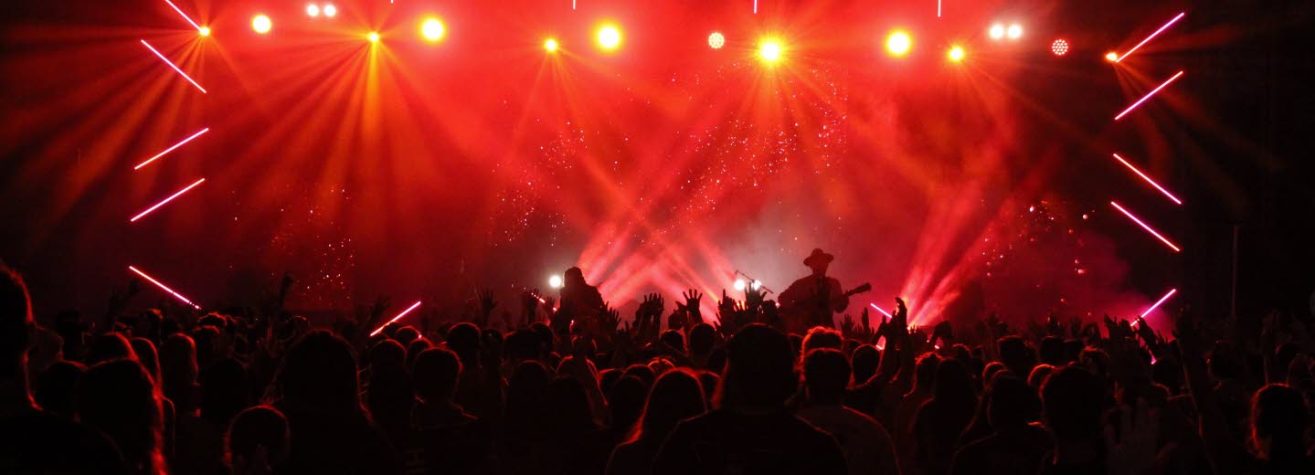 Konsertscen upplyst i rött ljus med publikhav framför.