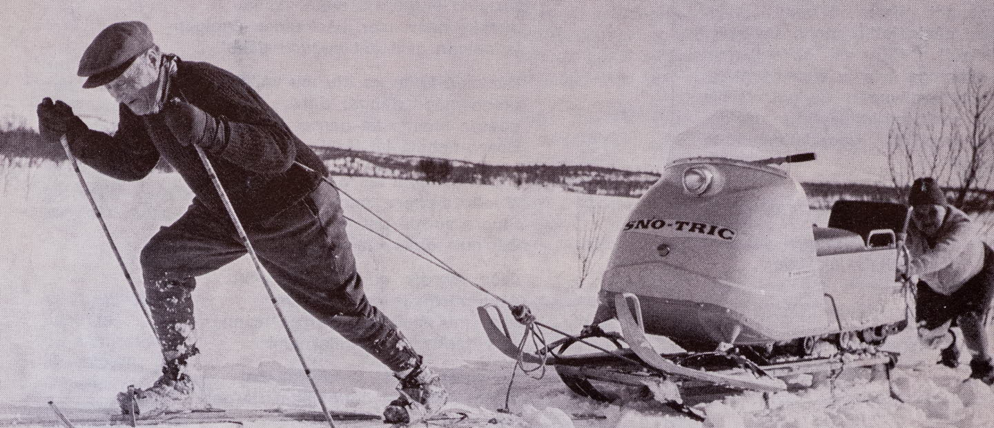 Man på arkivfoto på skidor som drar en skoter. 