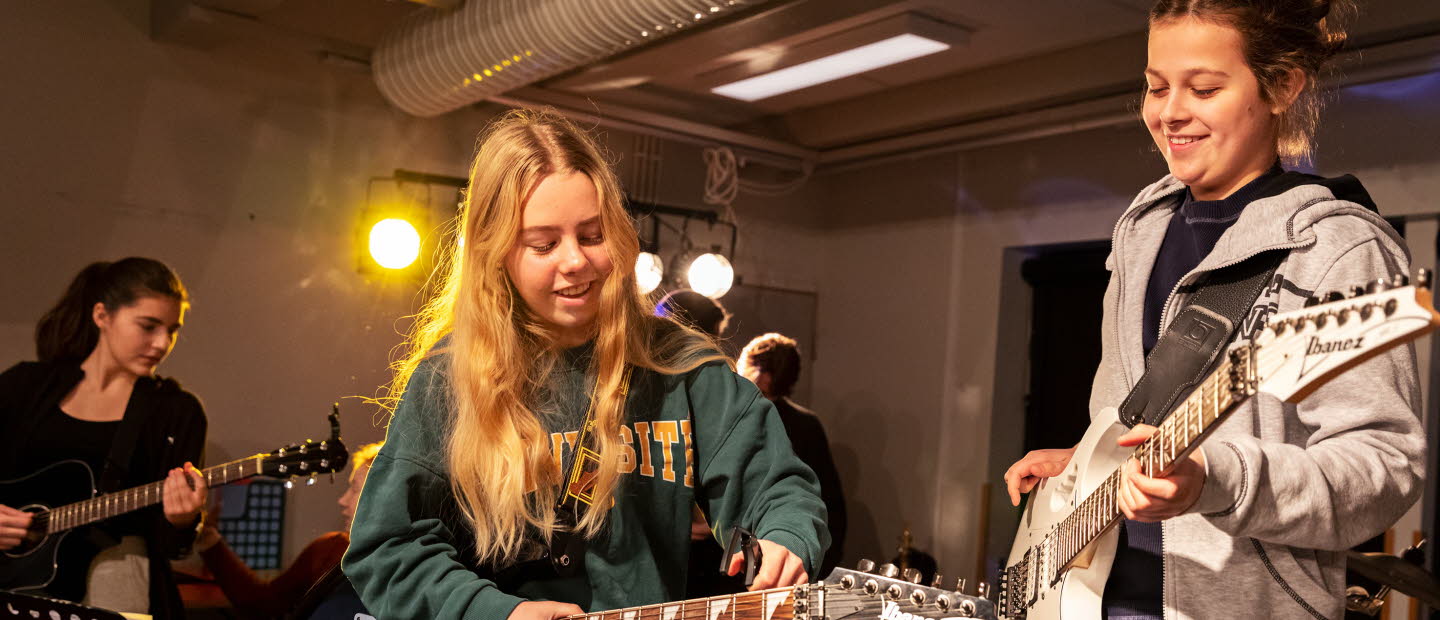 Tre tjejer spelar elgitarr.